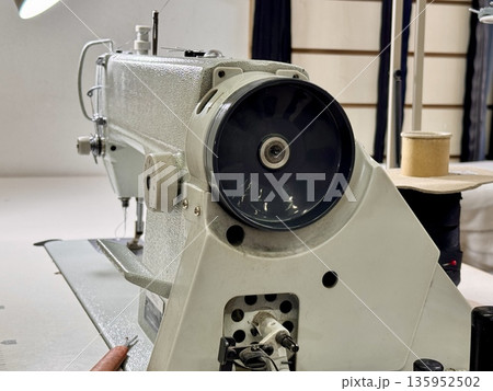 sewing workshop with a work area sewing machine filled with threads and working tools 135952502