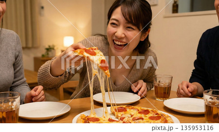 ペパロニピザのチーズに釘付け！友人たちと食卓を囲む賑やかな食事風景 135953116