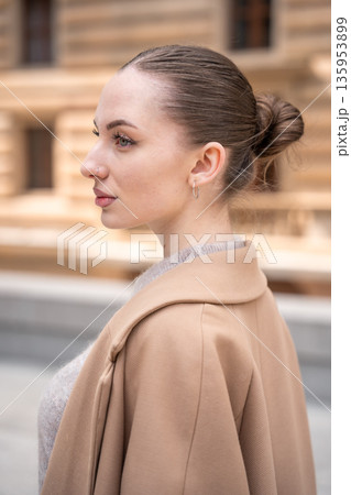 Portrait of young beautiful woman wearing coat walking in the city centre of Prague, Europe Portrait of young beautiful woman wearing coat walking in the city centre of Prague, Europe 135953899