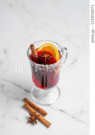 Glass of mulled wine, orange, cinnamon, and star anise on a marble background with spice. Glass of mulled wine, orange, cinnamon, and star anise on a marble background with spice. 135954071