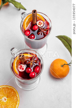 Two glasses of mulled wine, orange, cinnamon, and star anise on a light background close up Two glasses of mulled wine, orange, cinnamon, and star anise on a light background close up 135954077