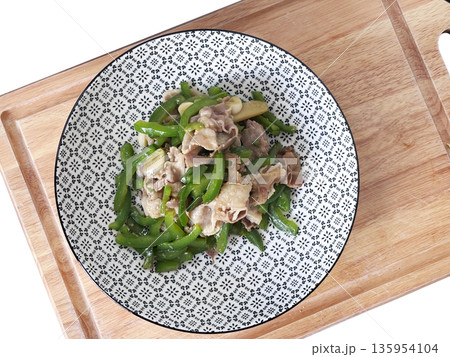 Still of a plate of stir-fried green bell pepper and thinly sliced pork, served in a patterned bowl on a wooden cutting board Still of a plate of stir-fried green bell pepper and thinly sliced pork, served in a patterned bowl on a wooden cutting board 135954104