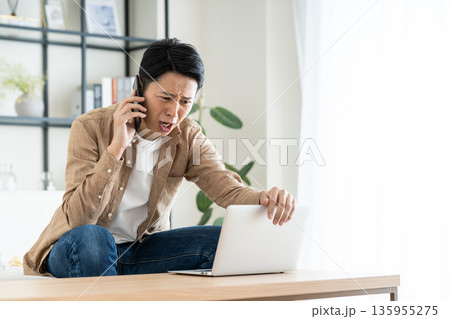 リビングでパソコンを使うミドルの男性 リビングでパソコンを使うミドルの男性 135955275