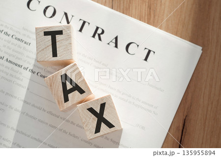 Word TAX on wooden cubes on contract documents background. Word TAX on wooden cubes on contract documents background. 135955894