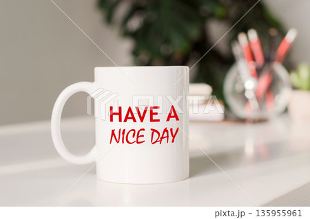 Coffee mug with text HAVE A NICE DAY in workplace background. 135955961