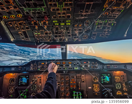 Pilots view from the cockpit of a classic jet flying at sunset over a winter landscape. 135956099