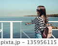 Beautiful young woman with a backpack on a background of the sea. Outdoors, lifestyle 135956115