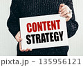 Girl holding a card with text CONTENT STRATEGY. 135956121