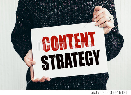 Girl holding a card with text CONTENT STRATEGY. 135956121