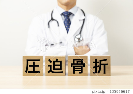 「圧迫骨折」と書かれたブロックと医師 135956617