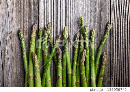 Fresh green asparagus stalks aligned neatly on wooden table Fresh green asparagus stalks aligned neatly on wooden table 135956742