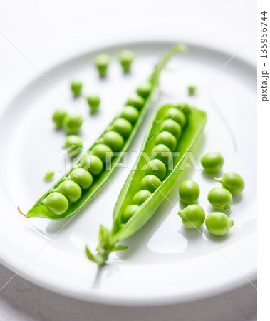 Fresh green peas arranged on a white plate in bright light Fresh green peas arranged on a white plate in bright light 135956744