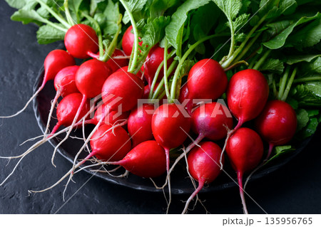 Fresh washed radishes on black plate against dark background 135956765
