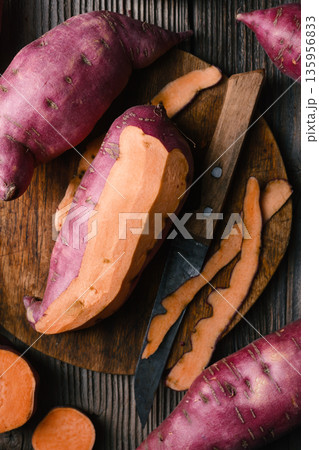 Raw sweet potato with cut pieces on dark wooden surface 135956833
