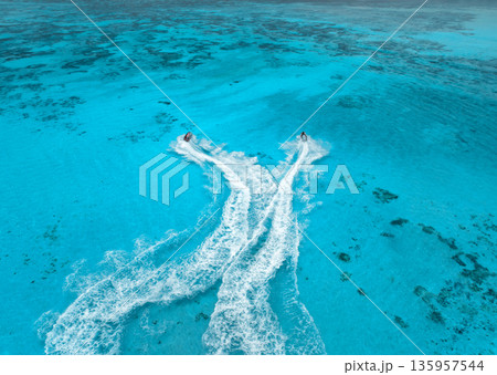 Aerial view of jet skis over shallow turquoise sea with reef Aerial view of jet skis over shallow turquoise sea with reef 135957544