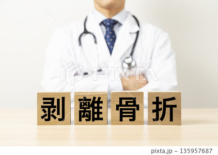 「剥離骨折」と書かれたブロックと医師 135957687
