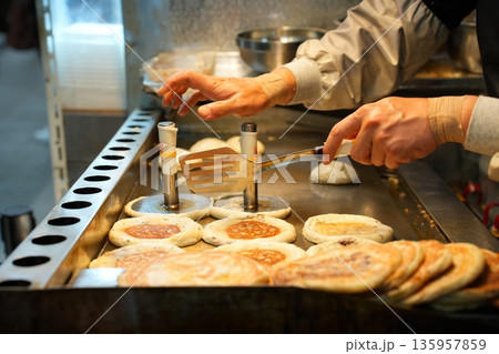 Hotteok Sweet Korean Pancake Being Cooked on a Griddle 135957859