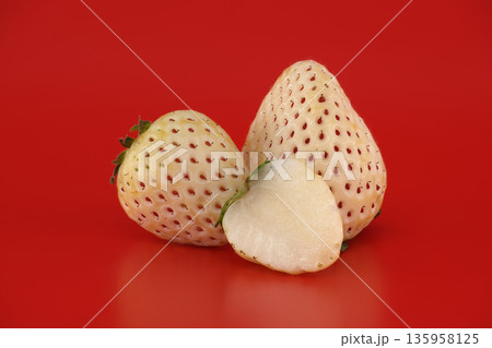 Unique pineberry strawberries with white flesh and red seeds on a vibrant red background Unique pineberry strawberries with white flesh and red seeds on a vibrant red background 135958125