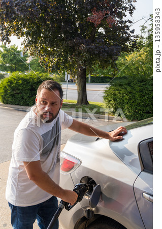 A man is filling up his car with gas 135958343