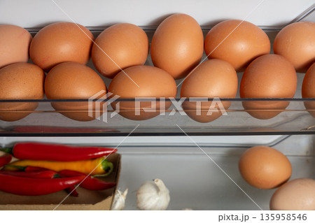 Storing eggs and vegetables on shelves on the refrigerator door. 135958546