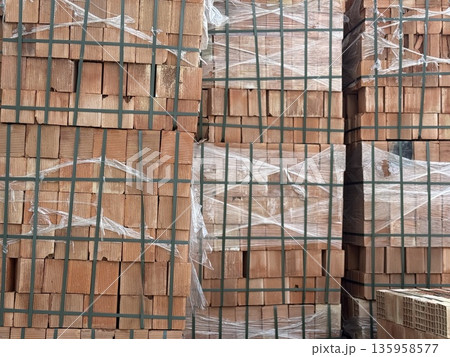 Stacked bricks in construction site tied with plastic wrap, creating textured background 135958577