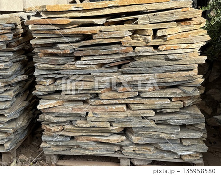 Stacked stone slabs in sunlight creating textured natural background with earthy tones 135958580