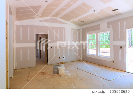 New room under construction shows installed drywall an empty space with no flooring finished. New room under construction shows installed drywall an empty space with no flooring finished. 135958629