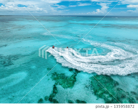 Aerial view of jet skis over shallow turquoise sea with reef 135958872