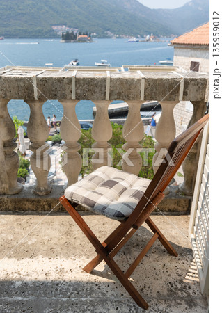 A wooden folding chair with a plaid cushion sits on a stone balcony A wooden folding chair with a plaid cushion sits on a stone balcony 135959012