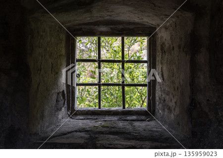 A small square window set in a rough stone wall 135959023
