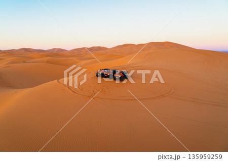 Dune adventure at sunset with multiple ATVs parked in the serene Sahara desert landscape 135959259