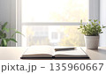 窓辺に置かれた観葉植物とノート｜自然光あふれるシンプルなデスク 135960667