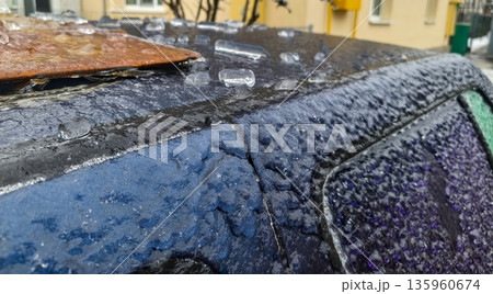 Rusty metal board atop icy vehicle roof with crystalline frost grains captures winter texture, cold accumulation, ice sheen and corroded metallic surface. 135960674