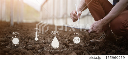Farmer checks soil quality by hand using digital data icons to analyze nutrients pH moisture with tablet 135960959