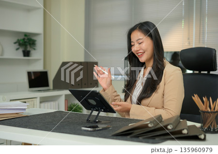 Asian woman has video conference with her remote team using digital tablet in office Asian woman has video conference with her remote team using digital tablet in office 135960979