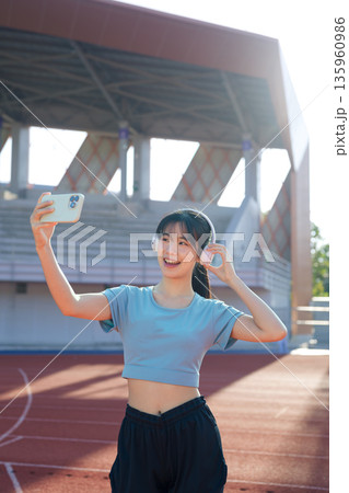 Woman taking selfie with smartphone at outdoor running track before workout Woman taking selfie with smartphone at outdoor running track before workout 135960986