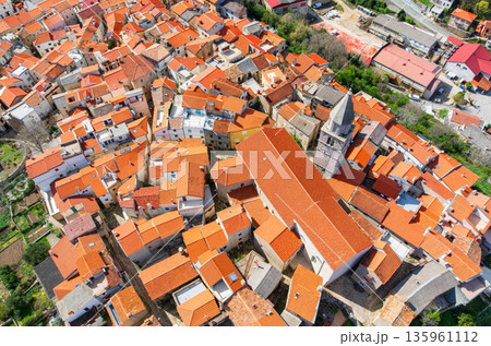 Drone captures stunning top view of Baska towns on Krk Island in Croatia. Blue Adriatic Sea meets rocky coastline and traditional Mediterranean architecture from above. 135961112