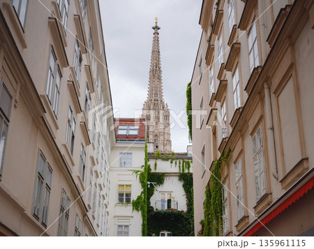 view from street on Historic Saint Stephens Cathedral on Stephansplatz square during summer day in Vienna. Tourists walk near Gothic architecture landmarks of Austrian capital city. view from street on Historic Saint Stephens Cathedral on Stephansplatz square during summer day in Vienna. Tourists walk near Gothic architecture landmarks of Austrian capital city. 135961115