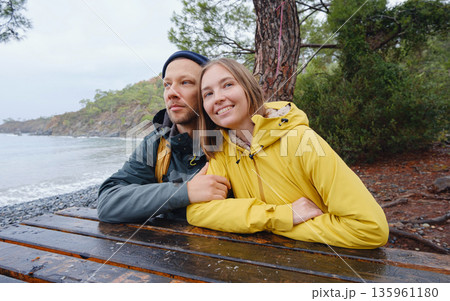 Couple enjoys Turkish coastline. walking in stone beach, watching sea waves, relaxing together, slow romantic moment near calm blue water under soft winter light. Couple enjoys Turkish coastline. walking in stone beach, watching sea waves, relaxing together, slow romantic moment near calm blue water under soft winter light. 135961180