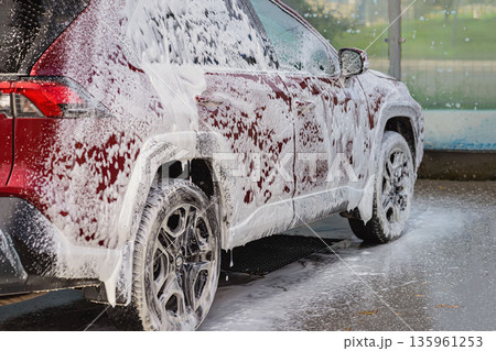 Car wash service, red SUV covered foam, self service car wash station. Red SUV covered with soap foam, car wash process, self service car wash station. Vehicle cleaning, automotive service concept 135961253