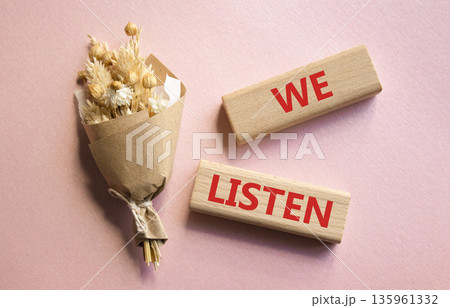 We listen symbol. Wooden blocks with words We listen. Beautiful pink background. Business and We listen concept. Copy space. 135961332