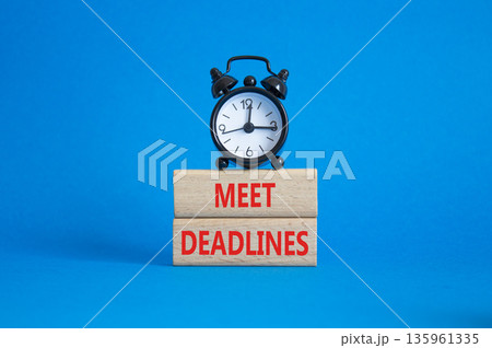 Meet Deadlines symbol. Concept word Meet Deadlines on wooden blocks. Beautiful blue background with alarm clock. Business and Meet Deadlines concept. Copy space Meet Deadlines symbol. Concept word Meet Deadlines on wooden blocks. Beautiful blue background with alarm clock. Business and Meet Deadlines concept. Copy space 135961335
