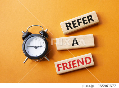 Refer a Friend symbol. Concept words Refer a Friend on wooden blocks. Beautiful orange background with alarm clock. Business and Refer a Friend concept. Copy space. 135961377