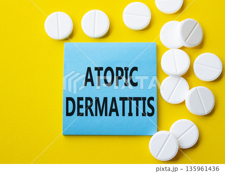 Atopic Dermatitis symbol. Concept word Atopic Dermatitis on blue note. Beautiful yellow background with pills. Medicine and Atopic Dermatitis concept. Copy space Atopic Dermatitis symbol. Concept word Atopic Dermatitis on blue note. Beautiful yellow background with pills. Medicine and Atopic Dermatitis concept. Copy space 135961436