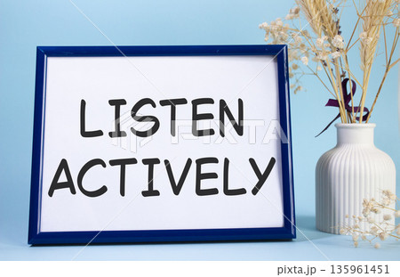 Listen actively symbol. Concept words Listen actively on beautiful wooden picture frame. Beautiful light blue background with flower vase. Business and Listen actively concept. Copy space. 135961451