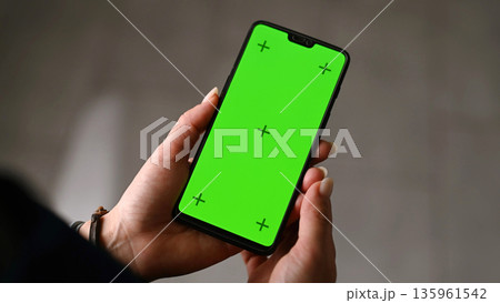 Girl Holding In Hands A Smartphone With Chroma Key Greenscreen With Motion Tracking Markers 135961542