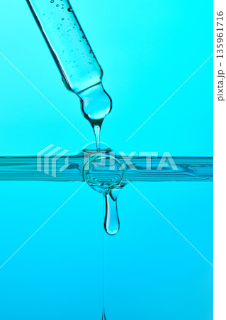Pipette dripping liquid forming drops onto water surface 135961716