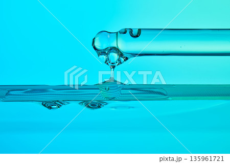 Pipette dripping clear serum into blue liquid Pipette dripping clear serum into blue liquid 135961721
