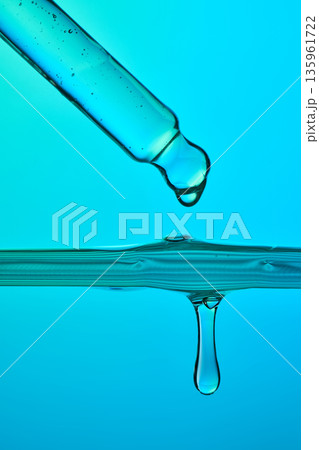 Hydrating serum droplet falling into blue liquid 135961722