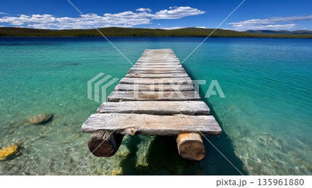 Wooden dock extends into clear turquoise water under a blue sky with clouds 135961880
